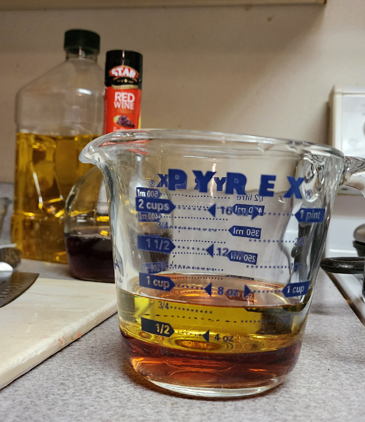 Measuring cup with  cup red wine vinegar and  cup olive oil