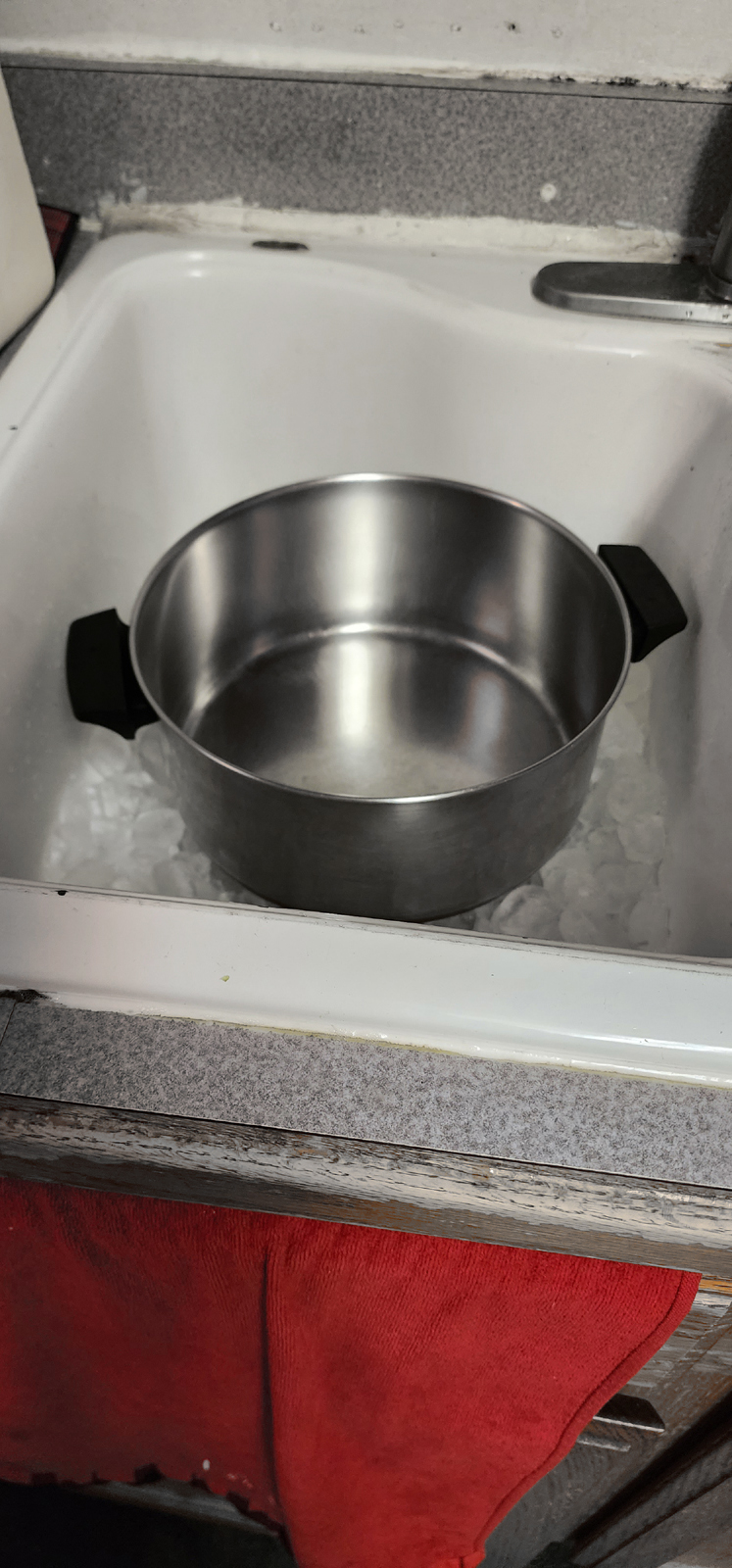 Stockpot on Ice at the bottom of a sink alonside of stock pot