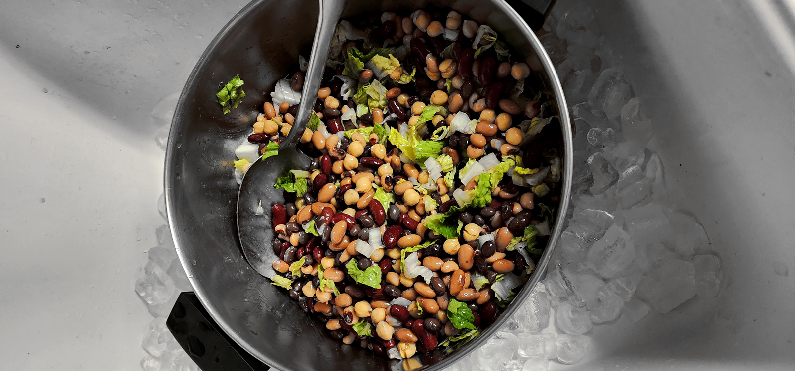 Mixed beans and diced lettuce in stock pot on the ice