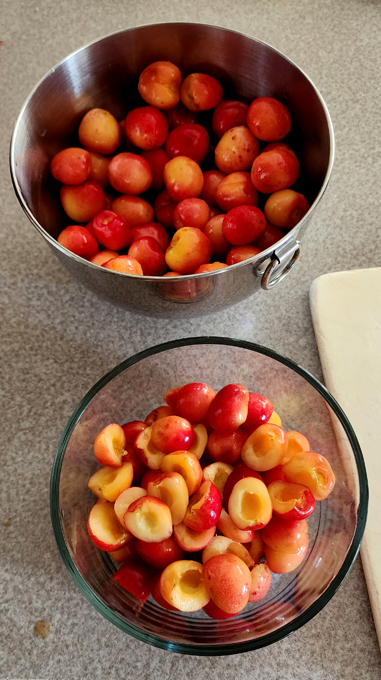 Photo of two bowls of which one contains cherries and the other containing cherry halves
