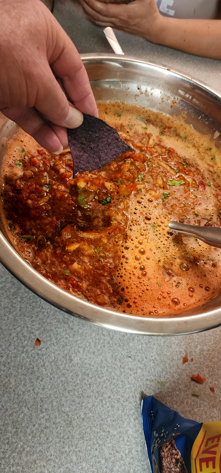 Dipping a chip in the mixing bowl of finished salsa